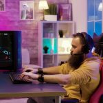 Bearded man playing video games in a room with colorful neons
